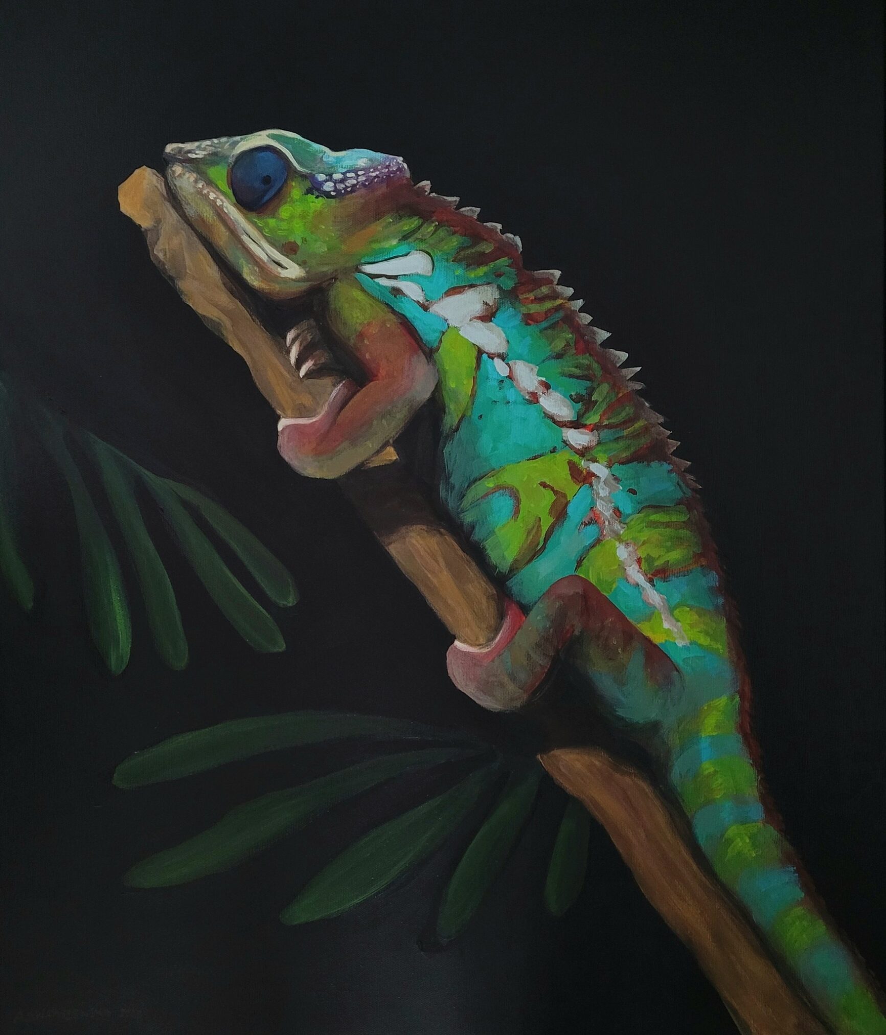 Kolorowy kameleon o jasnym turkusowo-zielonym ubarwieniu z niebieskim okiem siedzi na brązowej gałęzi wśród ciemnozielonych liści. Jaszczurka ma otwartą paszczę i charakterystyczne ciało z grzebieniem na grzbiecie, ukazane na ciemnym tle.